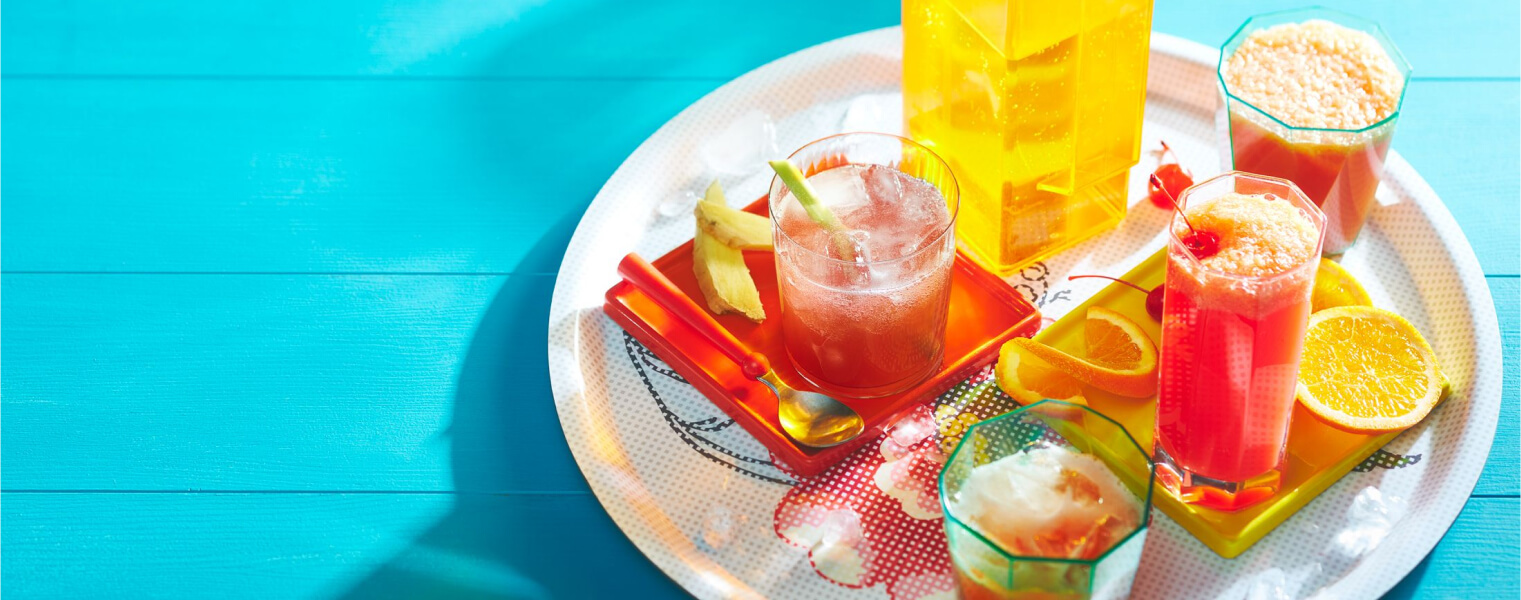 tropical sparkler and peachy sunrise mocktail drinks on a white round serving platter