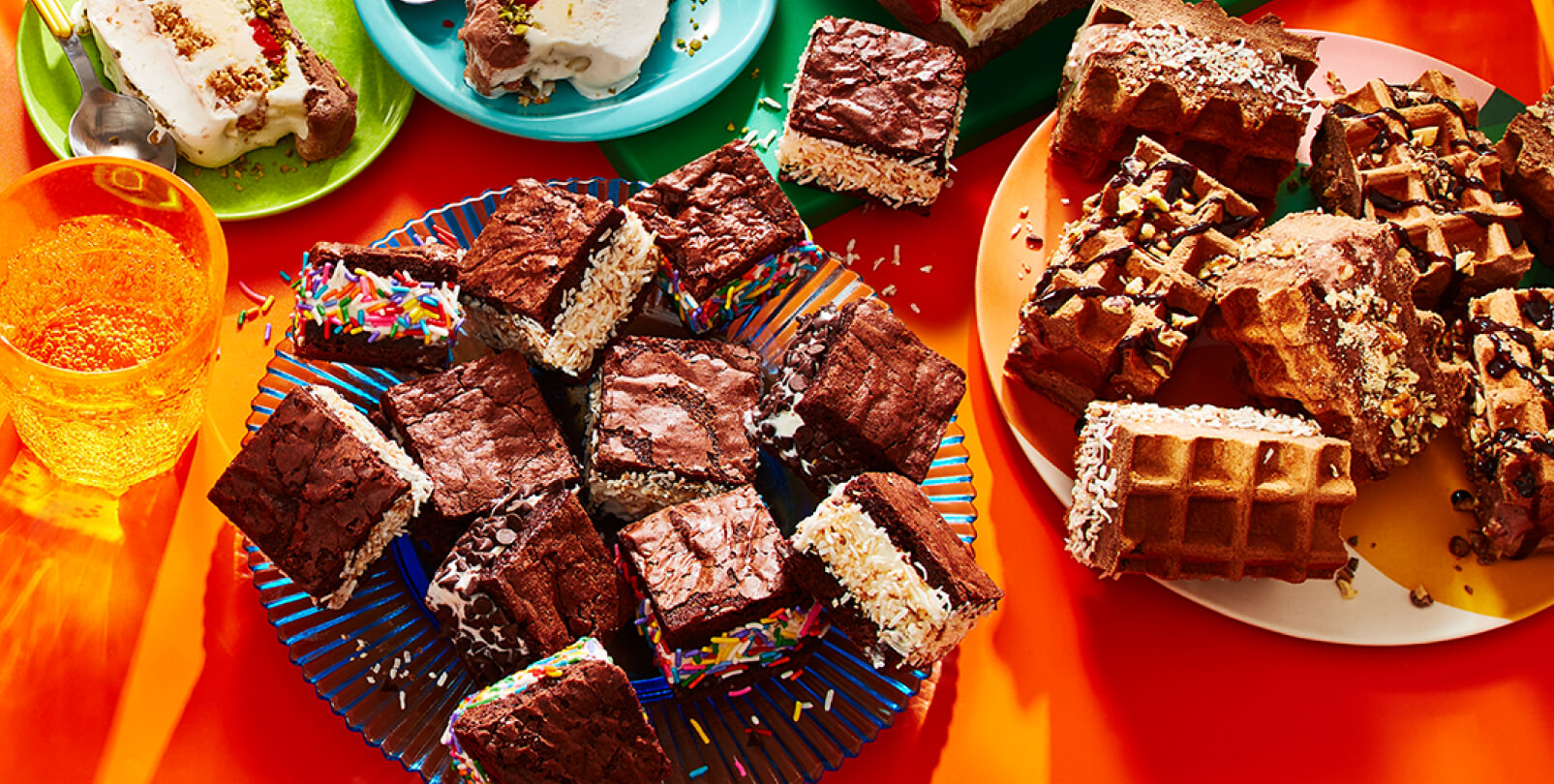 Double Chocolate Ice Cream Waffle sandwiches, brownie ice cream sandwiches, and layered ice cream loaf cake on an orange backdrop