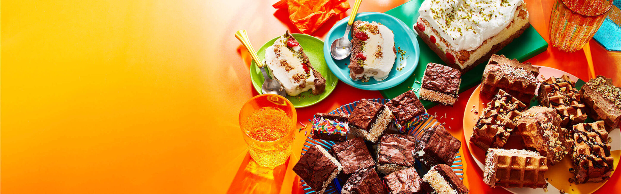 Double Chocolate Ice Cream Waffle sandwiches, brownie ice cream sandwiches, and layered ice cream loaf cake on an orange backdrop