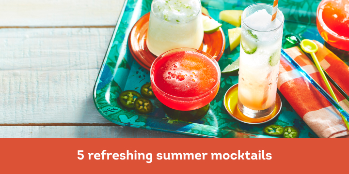 white wooden picnic table surface with aqua tray holding four colourful mocktails